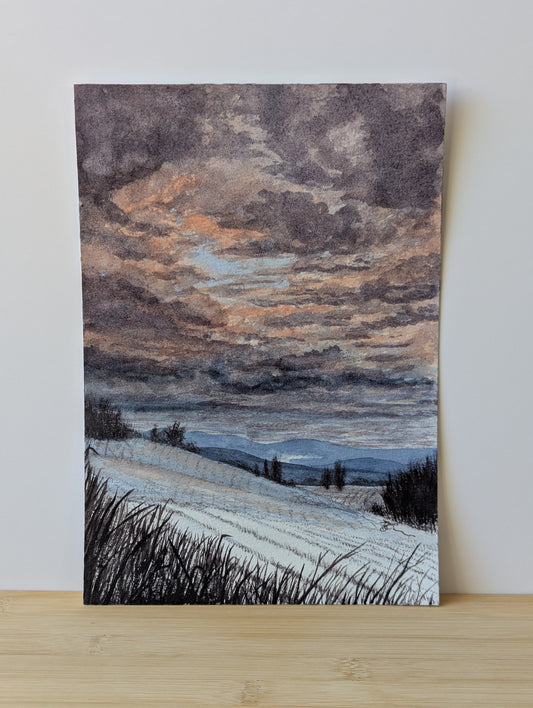 Painting of a landscape with a cloudy sky and fields on a wooden surface.