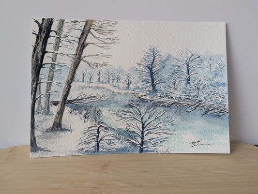 Winter landscape painting with trees and a lake on a wooden surface
